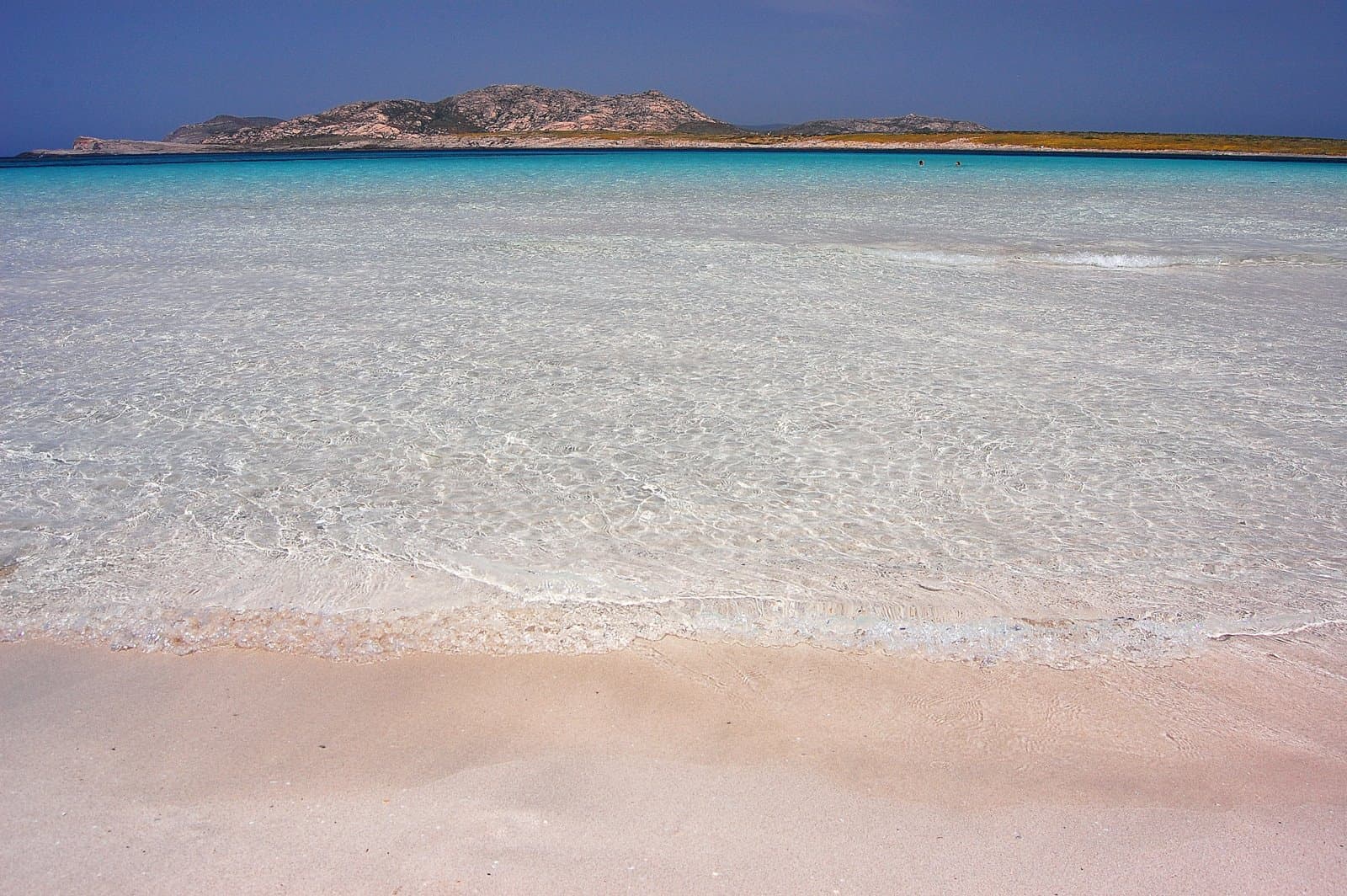 Shallow, crystal-clear turquoise water over white sand at La Pelosa, Stintino